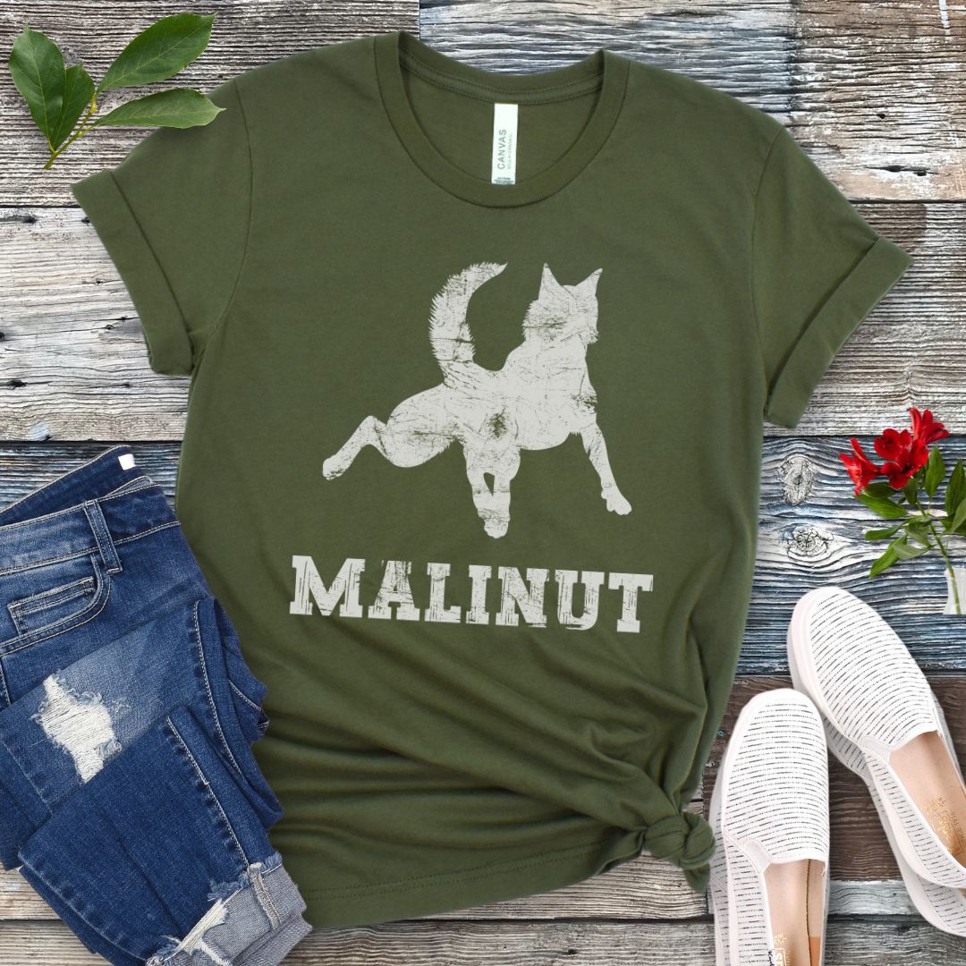 Military green t-shirt with leaping Belgian Malinois silhouette and 'MALINUT' text on a wooden surface with jeans and shoes.