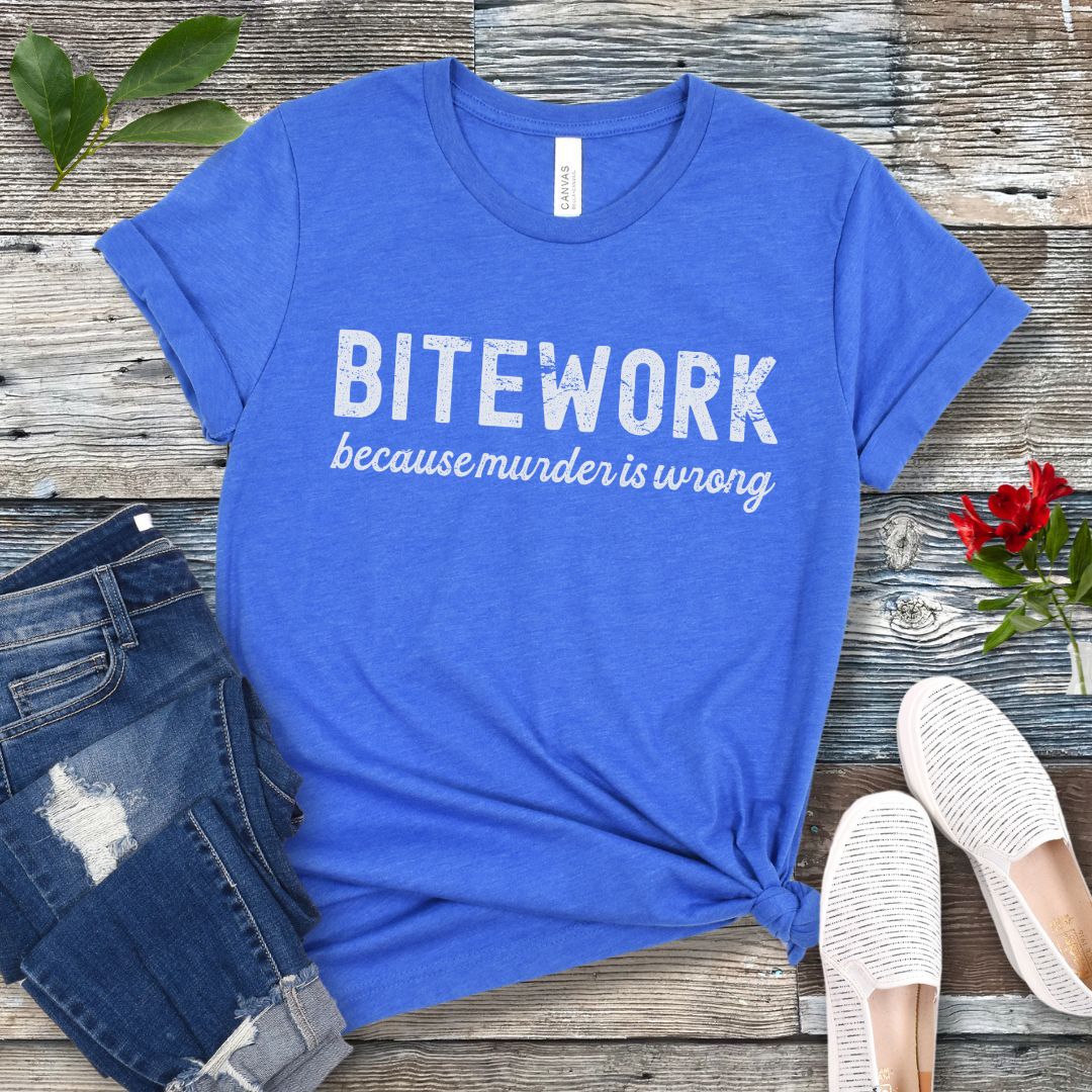 Royal blue Schutzhund t-shirt with 'BITEWORK because murder is wrong' text on a wooden surface with jeans and shoes.