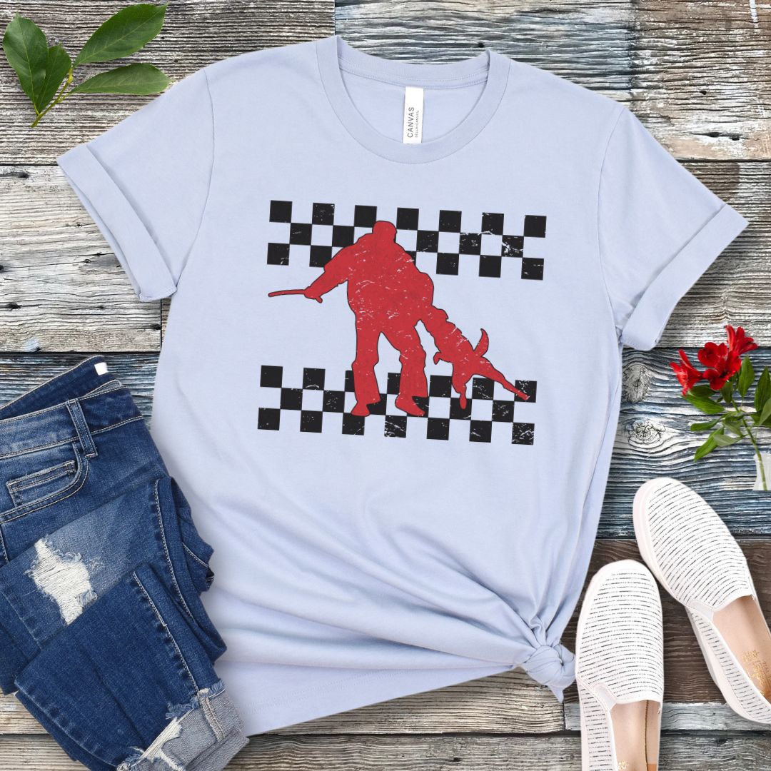 Light blue bitework t-shirt with protection dog, K9 helper, and checkerboard design, presented on a wooden surface with jeans and shoes.