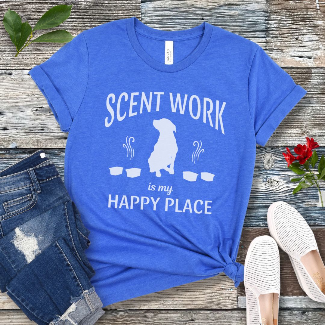Royal blue t-shirt with 'Scent Work is my Happy Place' text and dog silhouette on a wooden surface with jeans and shoes.