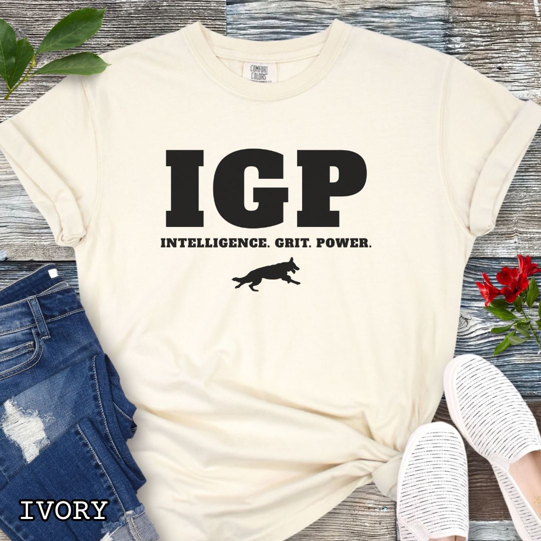 Beige Comfort Colors t-shirt featuring the IGP Intelligence. Grit. Power. design with working dog silhouette, Schutzhund shirt for IGP competitors, IPO handlers, protection sports enthusiasts, and working dog trainers.