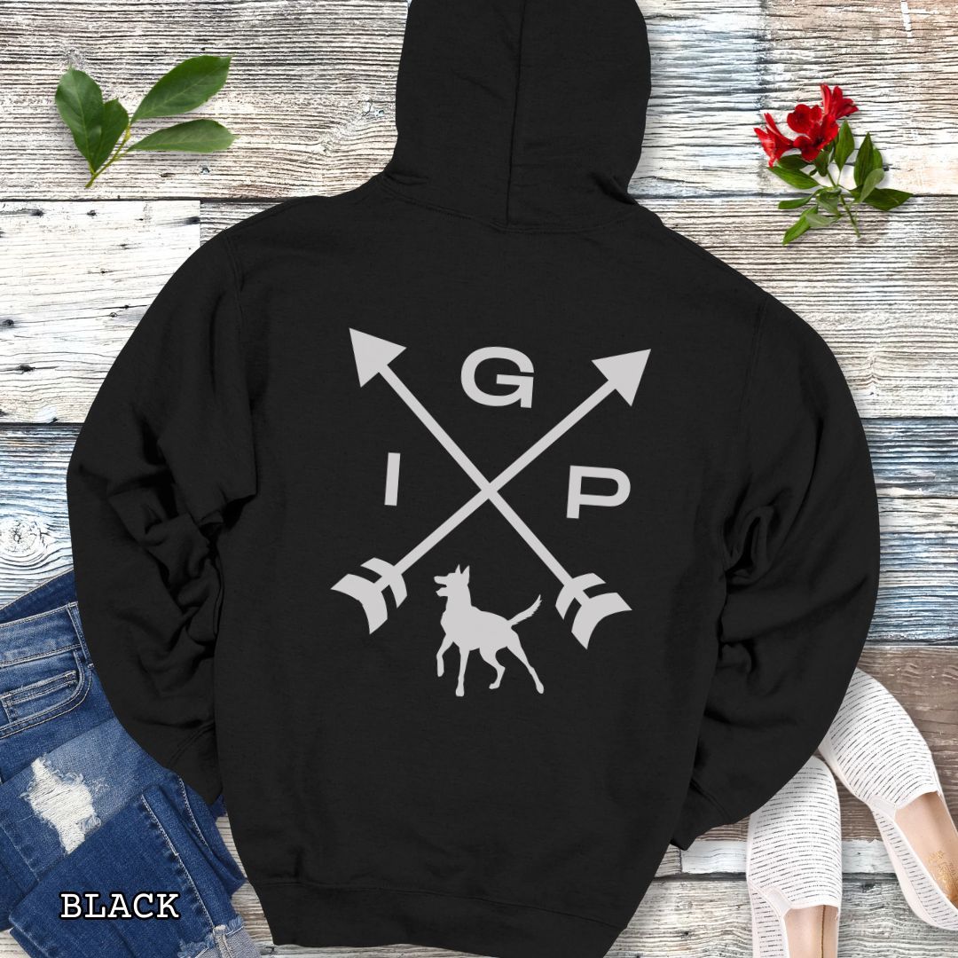 Black Schutzhund/IGP hoodie with crossed arrows design with 'IGP' text and Belgian Malinois on the back, presented on a wooden surface with accessories.