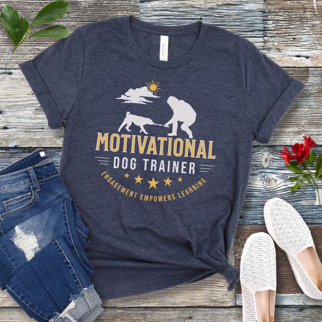 Blue t-shirt with 'Motivational Dog Trainer' design on a wooden surface with jeans and shoes.