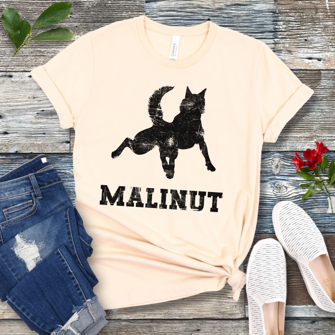 Beige dog lover t-shirt with leaping Belgian Malinois silhouette and 'MALINUT' text on a wooden surface with jeans and shoes.