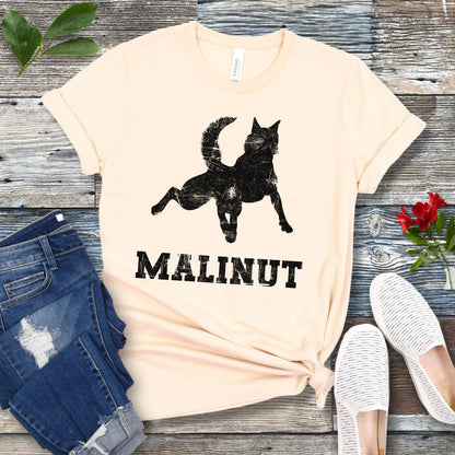 Beige dog lover t-shirt with leaping Belgian Malinois silhouette and 'MALINUT' text on a wooden surface with jeans and shoes.