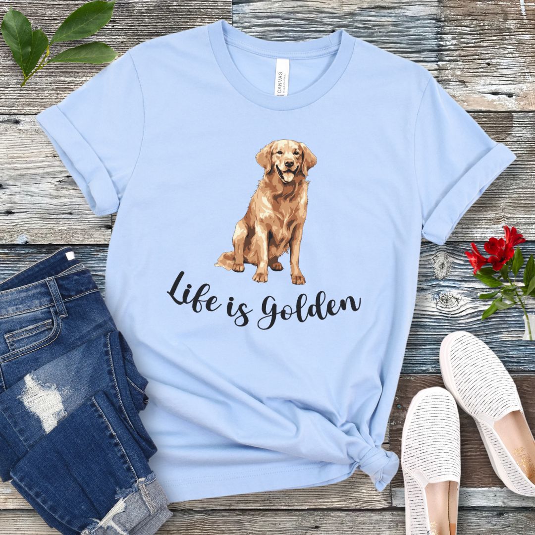 Light blue t-shirt with a Golden Retriever illustration and 'Life is Golden' text on a wooden surface with jeans and shoes.