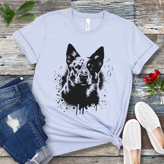 A light blue unisex t-shirt with a graphic of a Heeler/Cattle Dog done in street art style, displayed on a wooden surface, with a stylized image of a dog's face printed on the front.