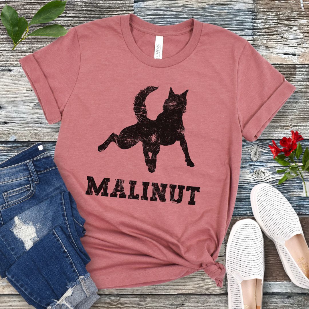 Mauve t-shirt with leaping Belgian Malinois silhouette and 'MALINUT' text on a wooden surface with jeans and shoes.