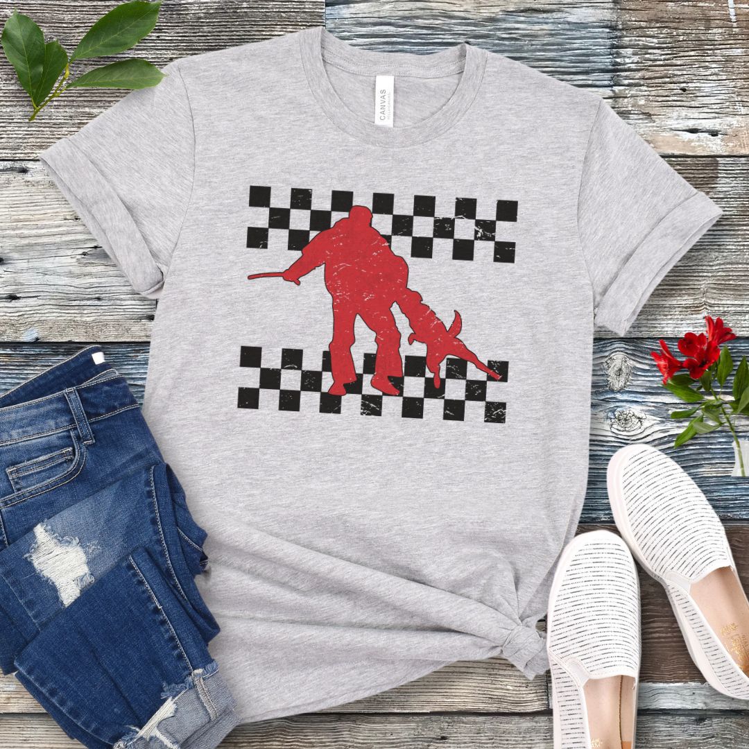 Light grey bite work t-shirt with protection dog, K9 helper, and checkerboard design, presented on a wooden surface with jeans and shoes.