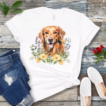 White dog lover t-shirt with a watercolor design of a Golden Retriever dog surrounded by colorful wildflowers, shown on a wooden surface with jeans and shoes.