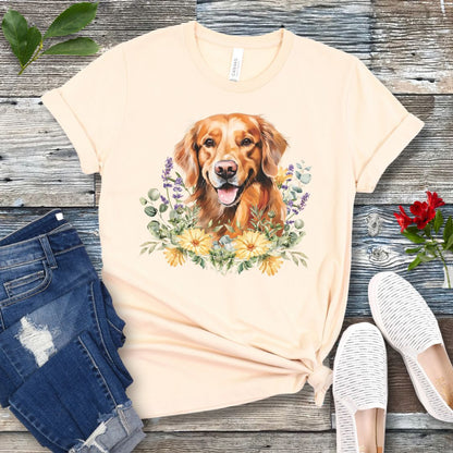 Beige dog lover t-shirt with a watercolor design of a Golden Retriever dog surrounded by colorful wildflowers, shown on a wooden surface with jeans and shoes.