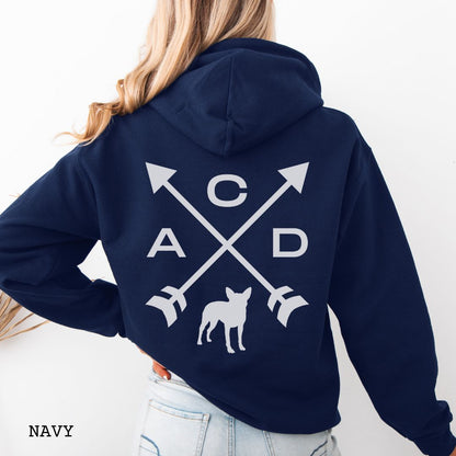 Navy Cattle Dog hoodie with back print design of crossed arrows, 'ACD' text and an Australian Heeler silhouette, worn by a person, on a white background.