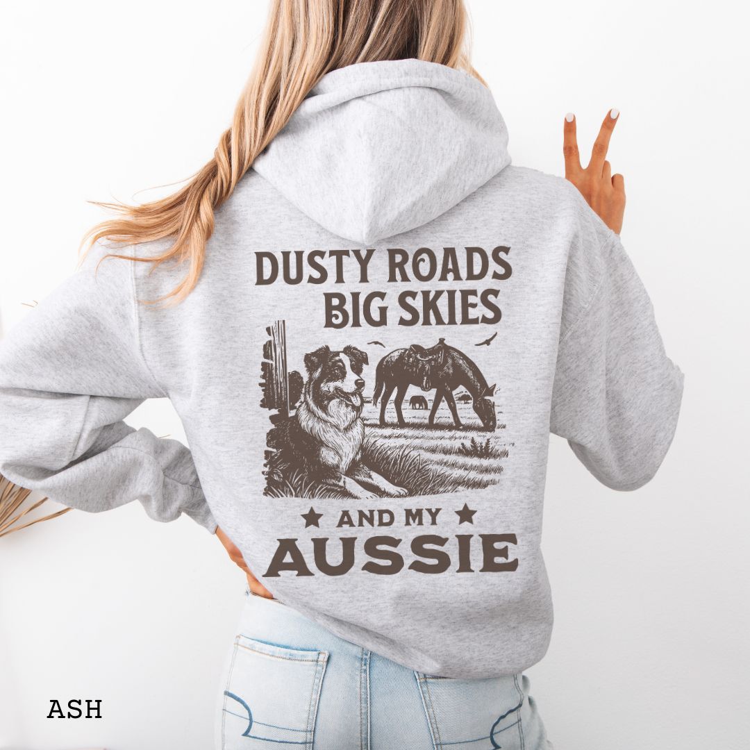 Back view of ash grey Australian Shepherd hoodie featuring a Western-style design with grazing horse, rustic fence, and an Australian Shepherd illustration; text reads “Dusty Roads, Big Skies, and My Aussie.”