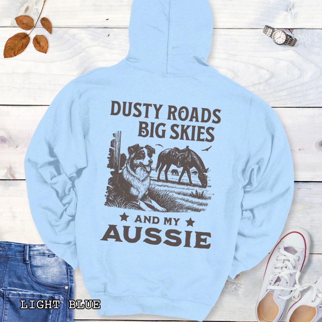 Back view of light blue Australian Shepherd hoodie featuring a Western-style design with grazing horse, rustic fence, and an Australian Shepherd illustration; text reads “Dusty Roads, Big Skies, and My Aussie.”