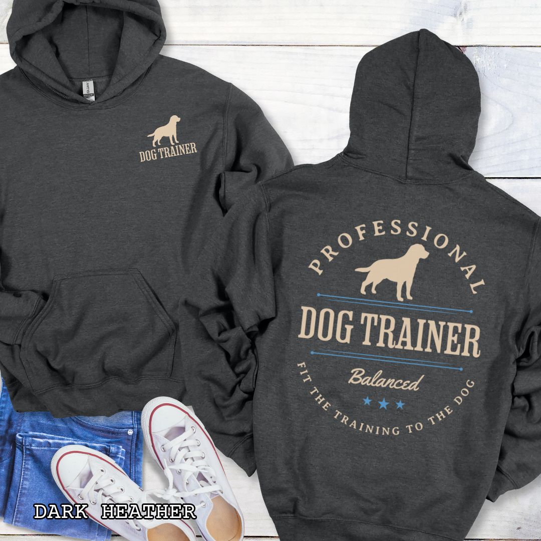 Front and back view of a dark grey dog training hoodie with the text 'PROFESSIONAL DOG TRAINER, Balanced, Fit the Training to the Dog"' and custom dog breed silhouette in a vintage, badge style design. The shirt is displayed flat with a pair of blue jeans and white shoes.