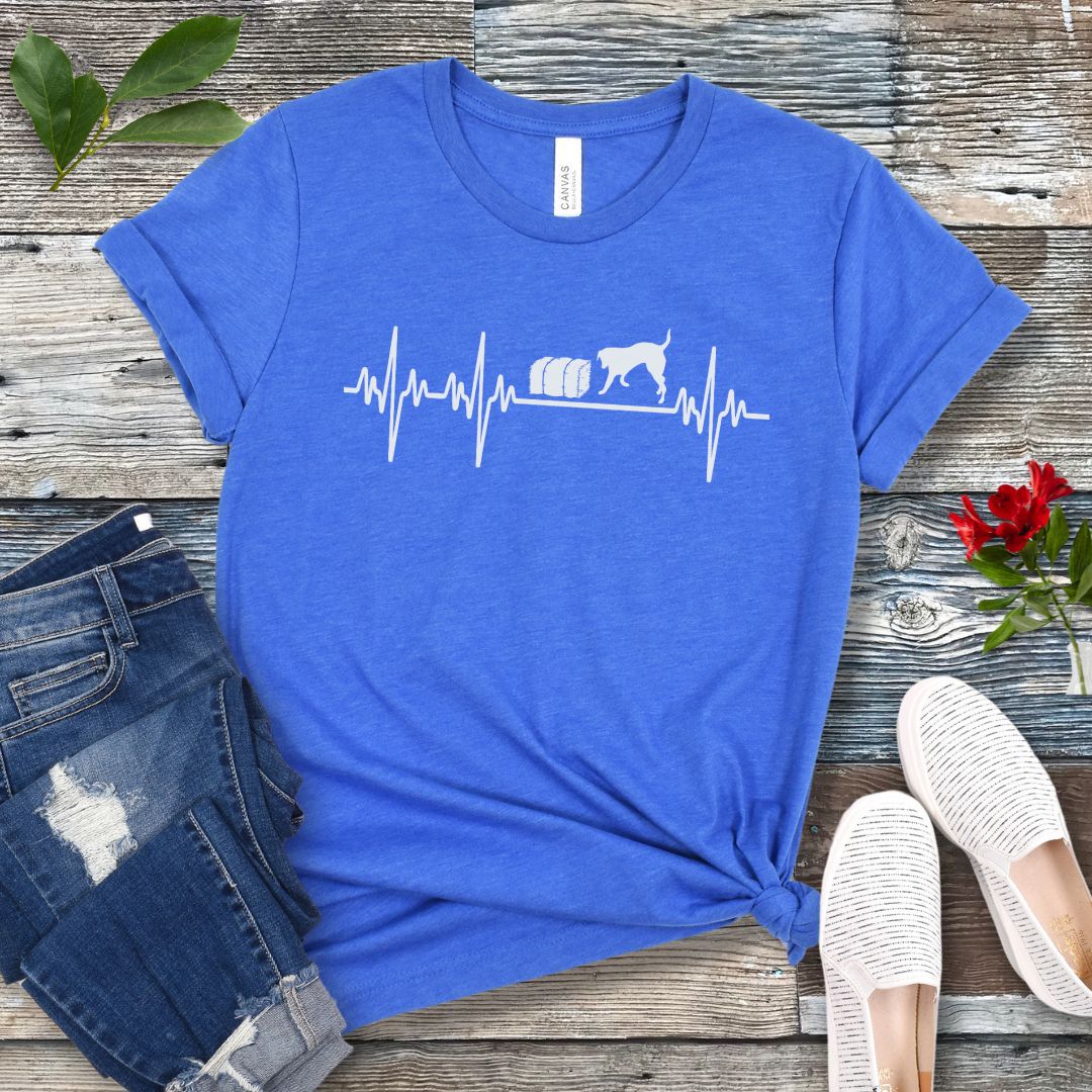 Blue dog sports t-shirt with heartbeat/EKG and barn hunt dog design on a wooden surface with jeans and shoes.