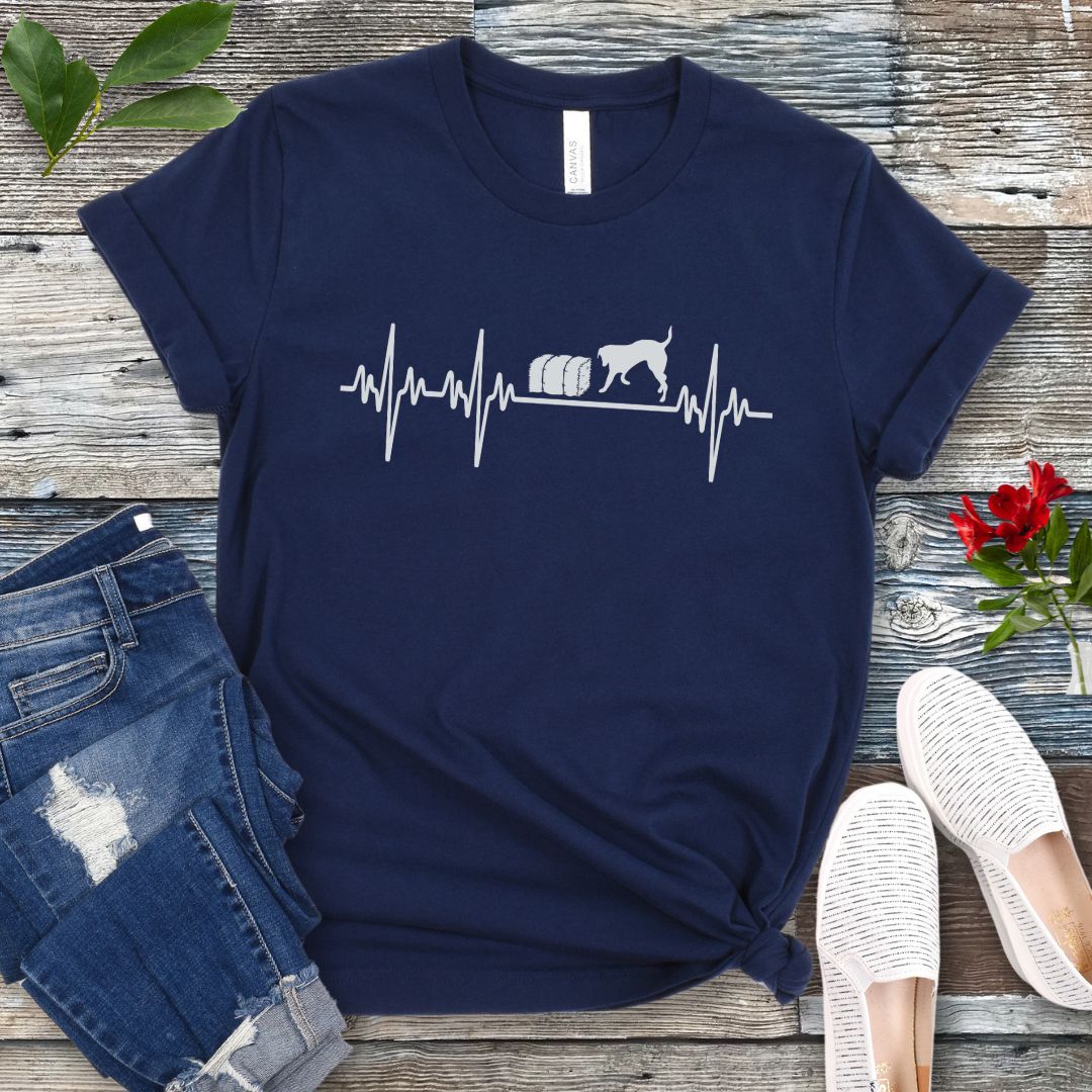 Navy blue dog sports t-shirt with heartbeat/EKG and barn hunt dog design on a wooden surface with jeans and shoes.
