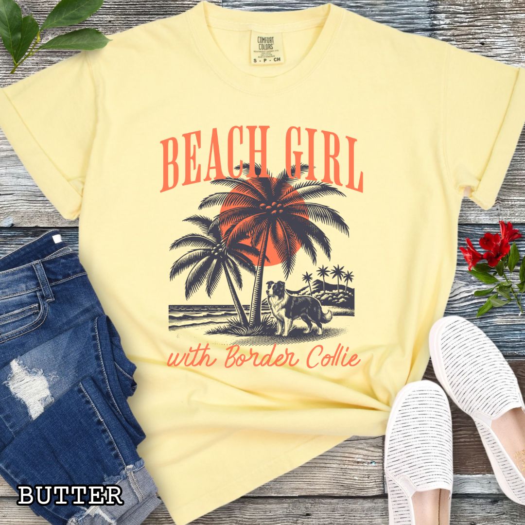 Yellow Comfort Colors t-shirt for Border Collie lovers with graphic of a Border Collie standing on a tropical beach, and the text 'Beach Girl With Border Collie' in retro lettering, shown on a wooden surface with accessories.