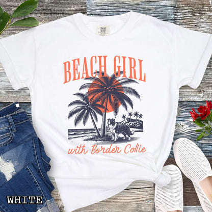 White Comfort Colors t-shirt for Border Collie lovers with graphic of a Border Collie standing on a tropical beach, and the text 'Beach Girl With Border Collie' in retro lettering, shown on a wooden surface with accessories.