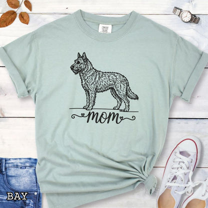 Light green Comfort Colors t-shirt with a vintage style illustration of a Belgian Laekenois and 'mom' text in feminine script beneath, shown on a wooden surface.