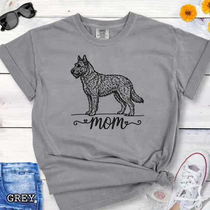 Grey Comfort Colors t-shirt with a vintage style illustration of a Belgian Laekenois and 'mom' text in feminine script beneath, shown on a wooden surface.