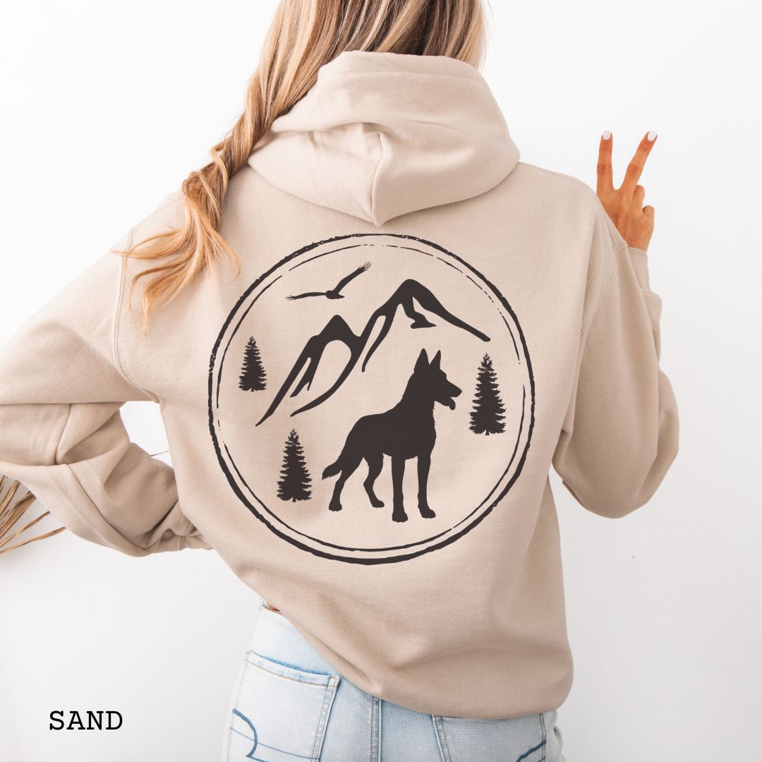 Sand colored Belgian Malinois hoodie featuring a bold vintage-style back print with Malinois silhouette, mountains, pine trees, perfect gift for hiking and outdoorsy Belgian Shepherd dog lovers.