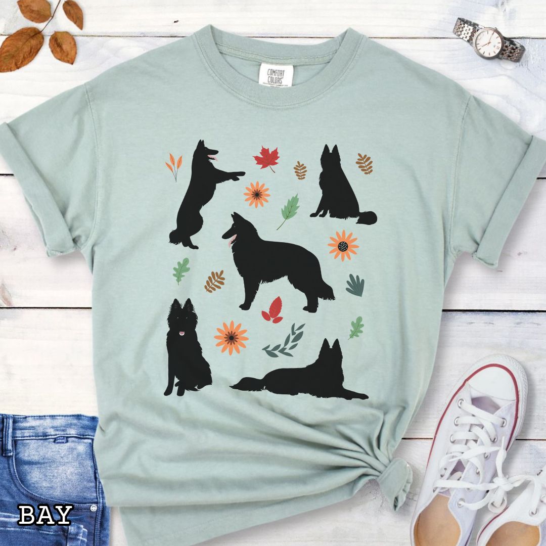 Light green cottagecore style dog lover t-shirt with Belgian Sheepdog silhouettes and colorful leaves on a wooden surface.