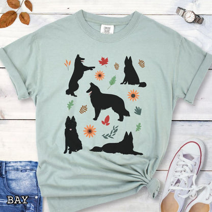 Light green cottagecore style dog lover t-shirt with Belgian Sheepdog silhouettes and colorful leaves on a wooden surface.