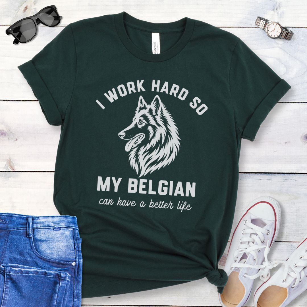 Dark green unisex t-shirt for Belgian Sheepdog lovers with breed head study graphic and humorous text 'I work hard so my Belgian can have a better life', shown on a wooden surface with jeans and shoes. 