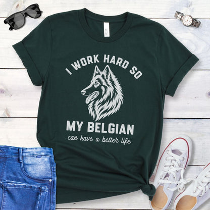 Dark green unisex t-shirt for Belgian Sheepdog lovers with breed head study graphic and humorous text 'I work hard so my Belgian can have a better life', shown on a wooden surface with jeans and shoes. 