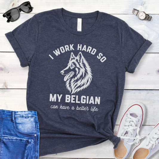 Heather navy blue unisex t-shirt for Belgian Sheepdog lovers with breed head study graphic and humorous text 'I work hard so my Belgian can have a better life', shown on a wooden surface with jeans and shoes. 