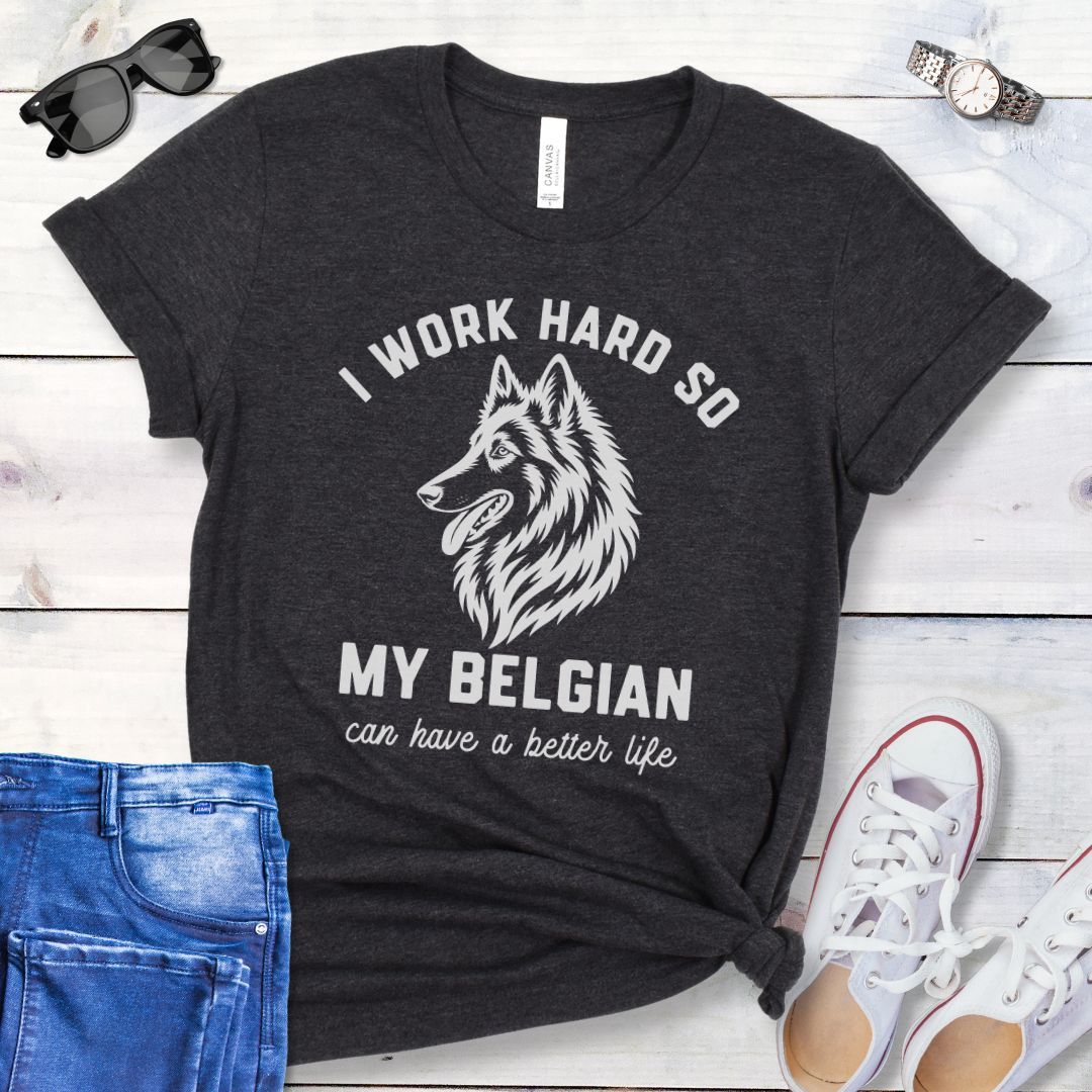 Dark grey unisex t-shirt for Belgian Sheepdog lovers with breed head study graphic and humorous text 'I work hard so my Belgian can have a better life', shown on a wooden surface with jeans and shoes. 