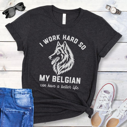 Dark grey unisex t-shirt for Belgian Sheepdog lovers with breed head study graphic and humorous text 'I work hard so my Belgian can have a better life', shown on a wooden surface with jeans and shoes. 
