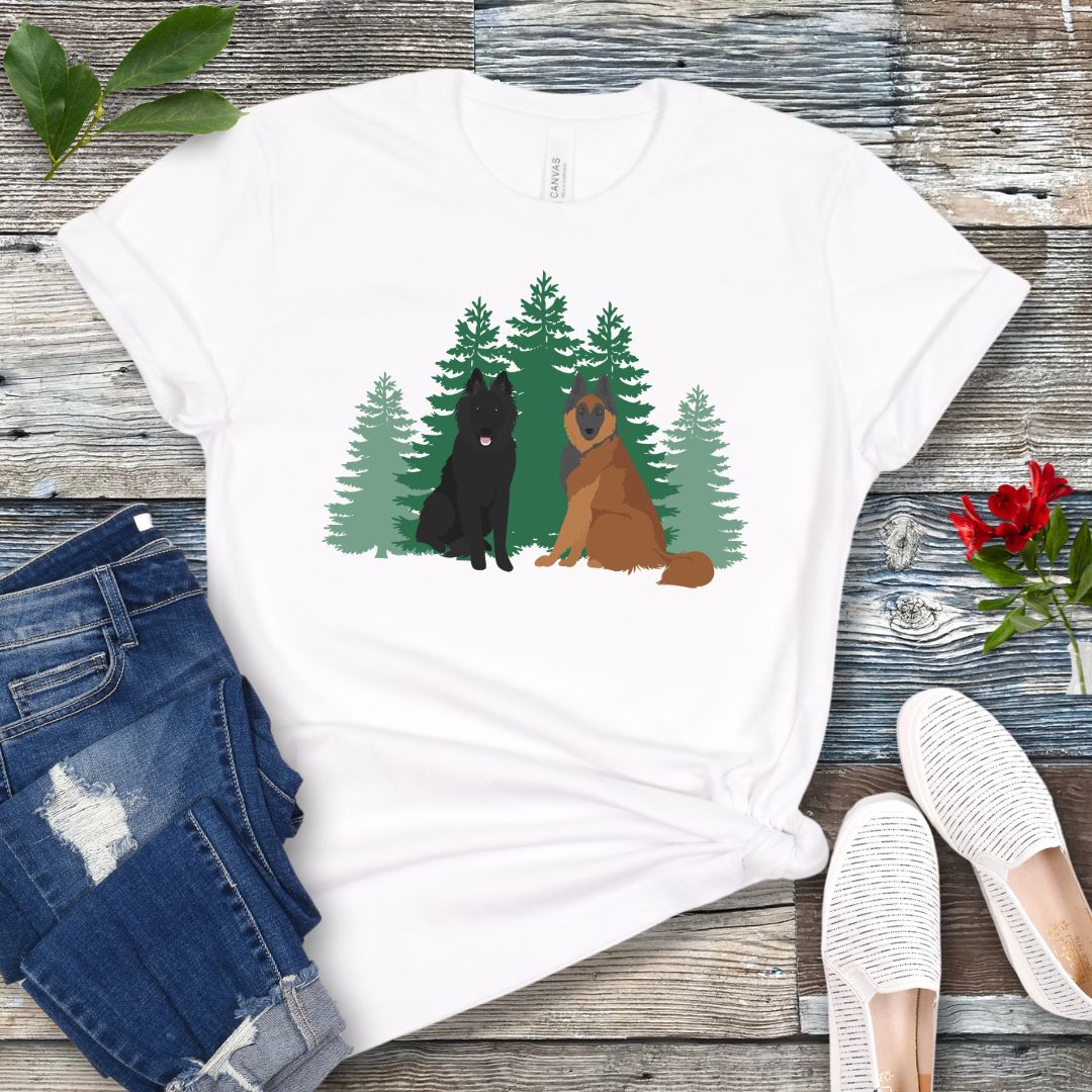 White Belgian Shepherd t-shirt with Belgian Sheepdog and Tervuren sitting in front of evergreen trees, shown on a wooden surface with jeans and shoes.