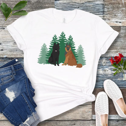 White Belgian Shepherd t-shirt with Belgian Sheepdog and Tervuren sitting in front of evergreen trees, shown on a wooden surface with jeans and shoes.