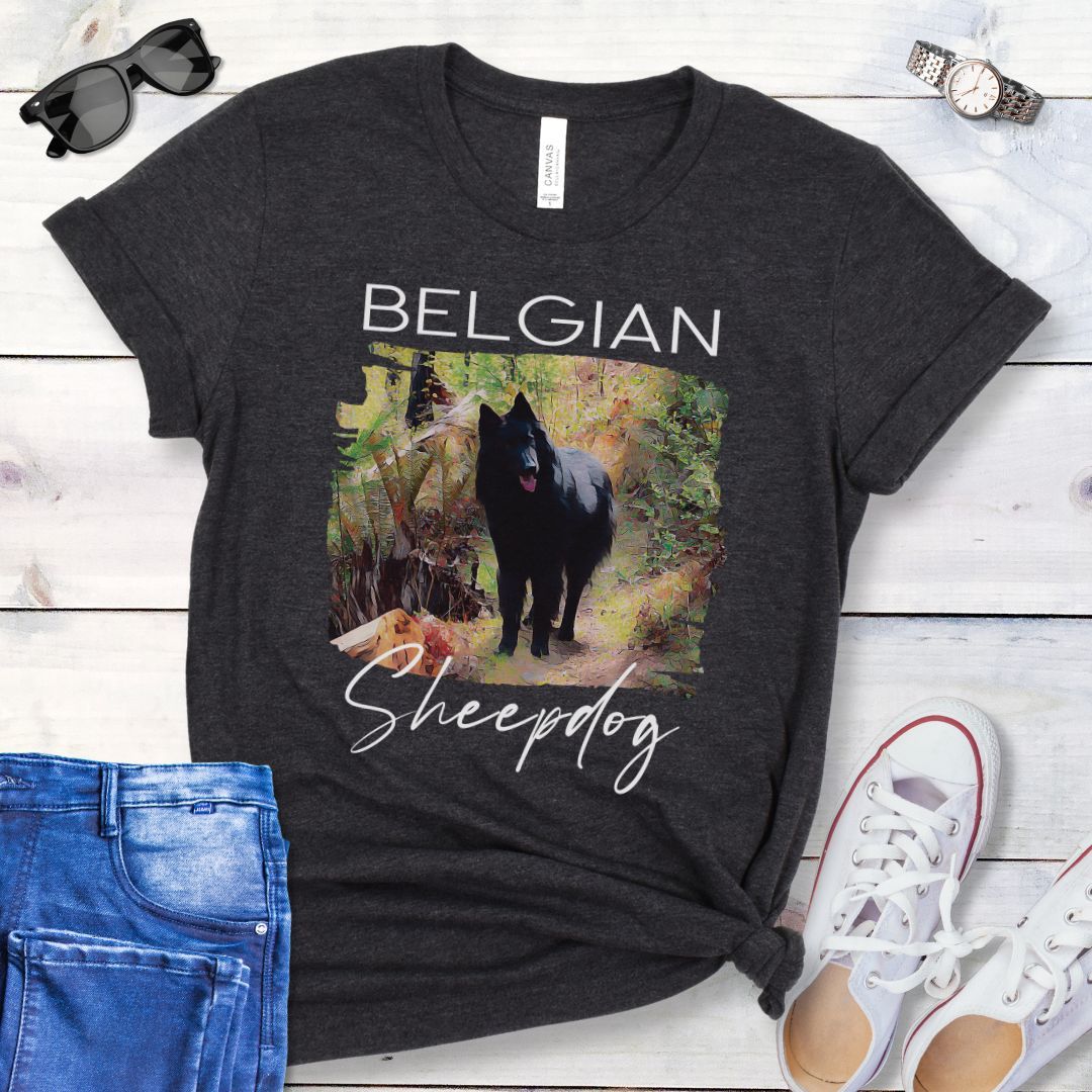Dark grey t-shirt with 'Belgian Sheepdog' text and a artistic illustration of a Belgian Sheepdog waiting on a woodland trail, shown on a wooden surface with jeans and shoes.