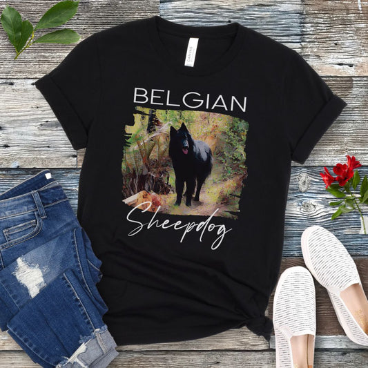 Black t-shirt with 'Belgian Sheepdog' text and a artistic illustration of a Belgian Sheepdog waiting on a woodland trail, shown on a wooden surface with jeans and shoes.