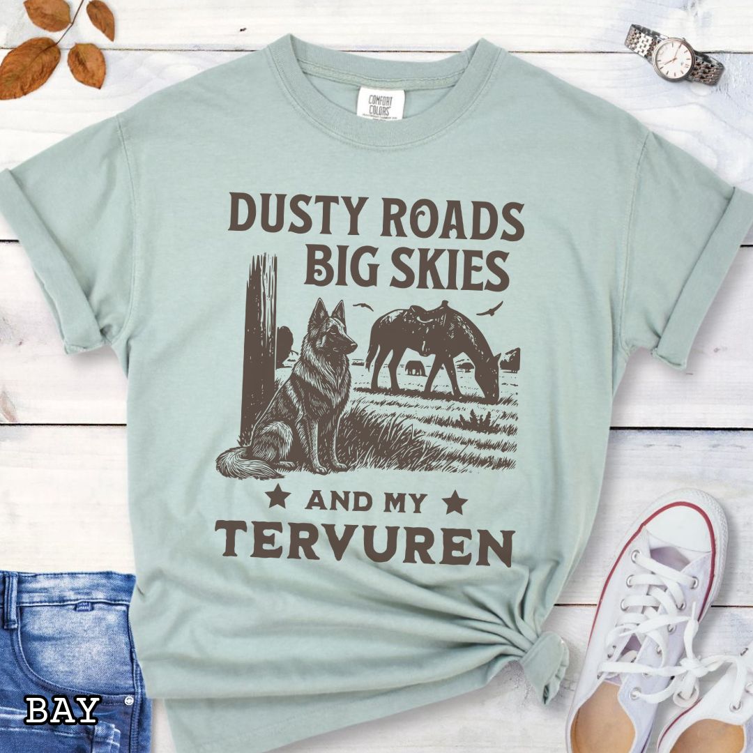 Light green Comfort Colors t-shirt featuring a Western-style design with grazing horse, rustic fence, and a Belgian Tervuren illustration; text reads “Dusty Roads, Big Skies, and My Tervuren.”