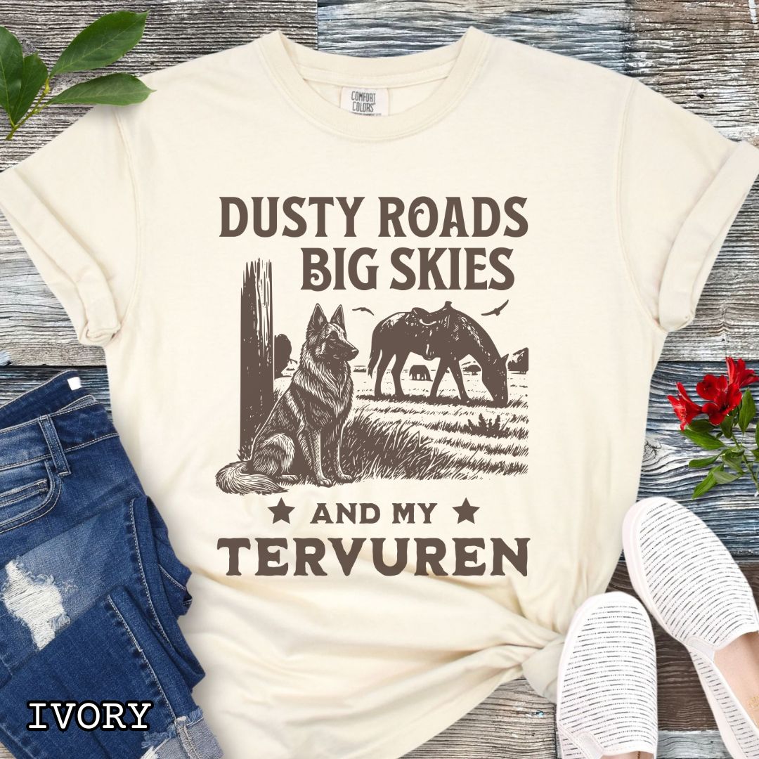Ivory Comfort Colors t-shirt featuring a Western-style design with grazing horse, rustic fence, and a Belgian Tervuren illustration; text reads “Dusty Roads, Big Skies, and My Tervuren.”