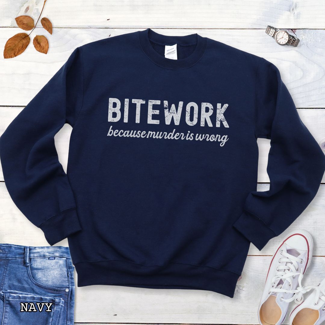 Navy Schutzhund sweatshirt with 'BITEWORK because murder is wrong' text on a wooden surface with jeans and shoes.