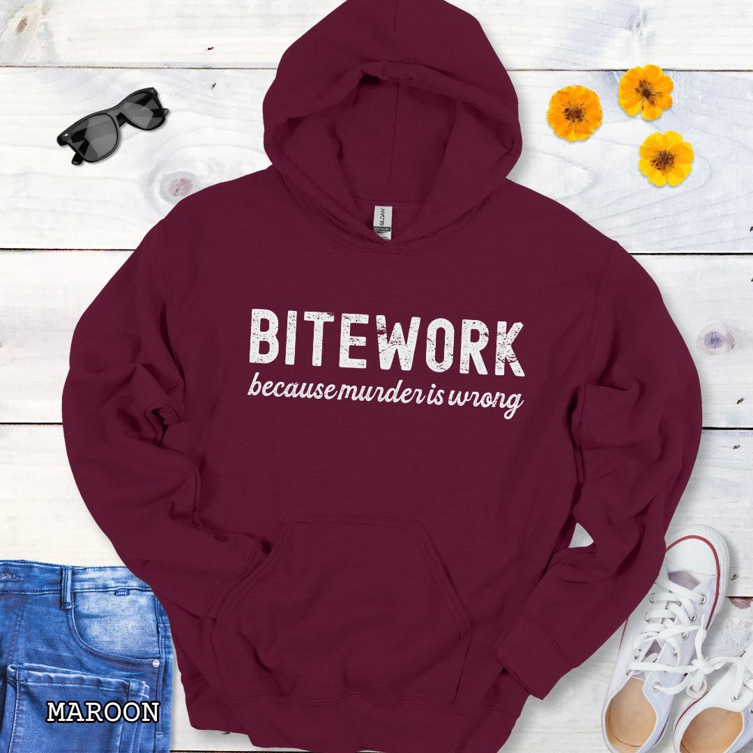 Maroon Schutzhund hoodie with 'BITEWORK because murder is wrong' text on a wooden surface with jeans and shoes.