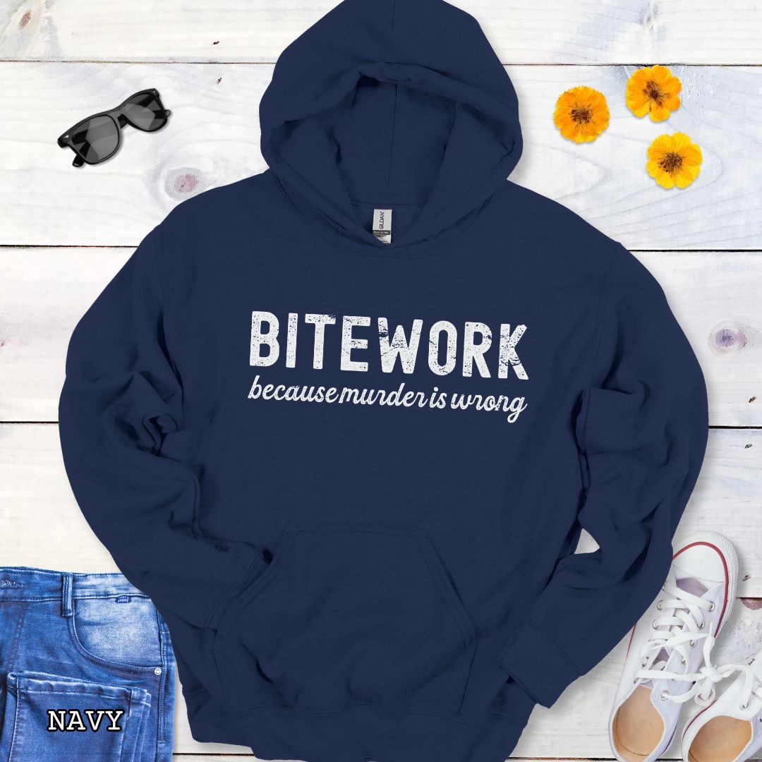 Navy blue sport dog hoodie with 'BITEWORK because murder is wrong' text on a wooden surface with jeans and shoes.
