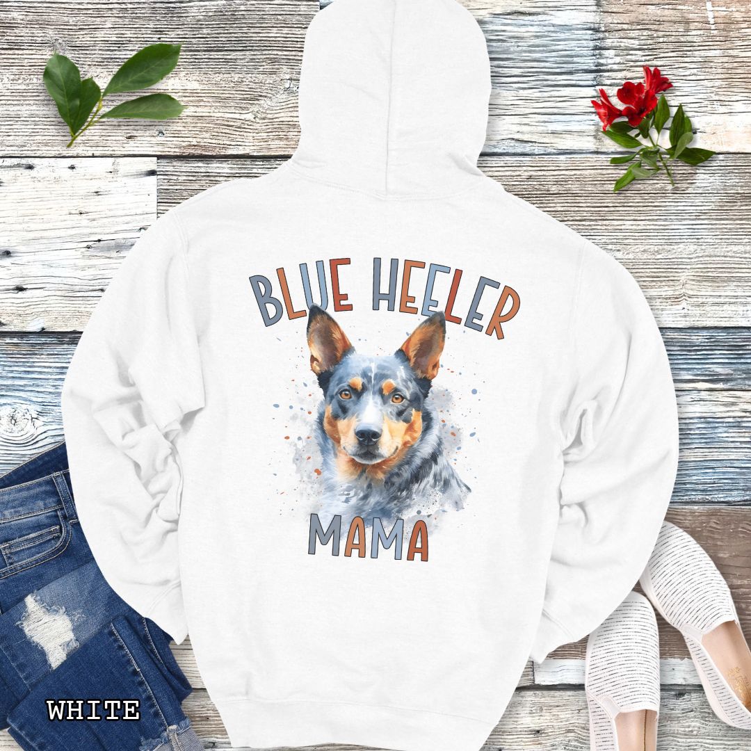 White Australian Cattle Dog hoodie with blue heeler graphic and 'Blue Heeler Mama' multicolor text on the back, presented on a wooden background with accessories.
