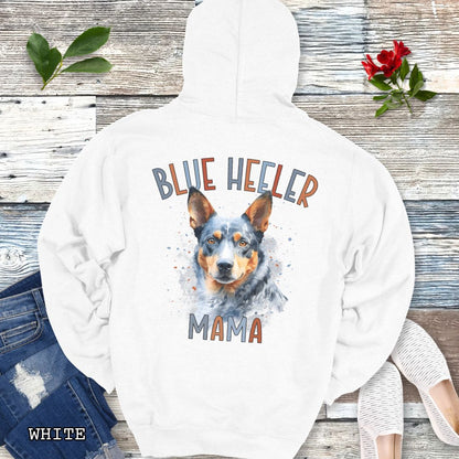 White Australian Cattle Dog hoodie with blue heeler graphic and 'Blue Heeler Mama' multicolor text on the back, presented on a wooden background with accessories.