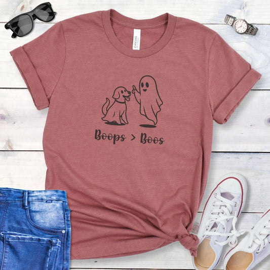 Mauve Halloween dog lover t-shirt with ghost and dog graphic and 'Boops > Boos' text, displayed with jeans and sneakers on a wooden surface.