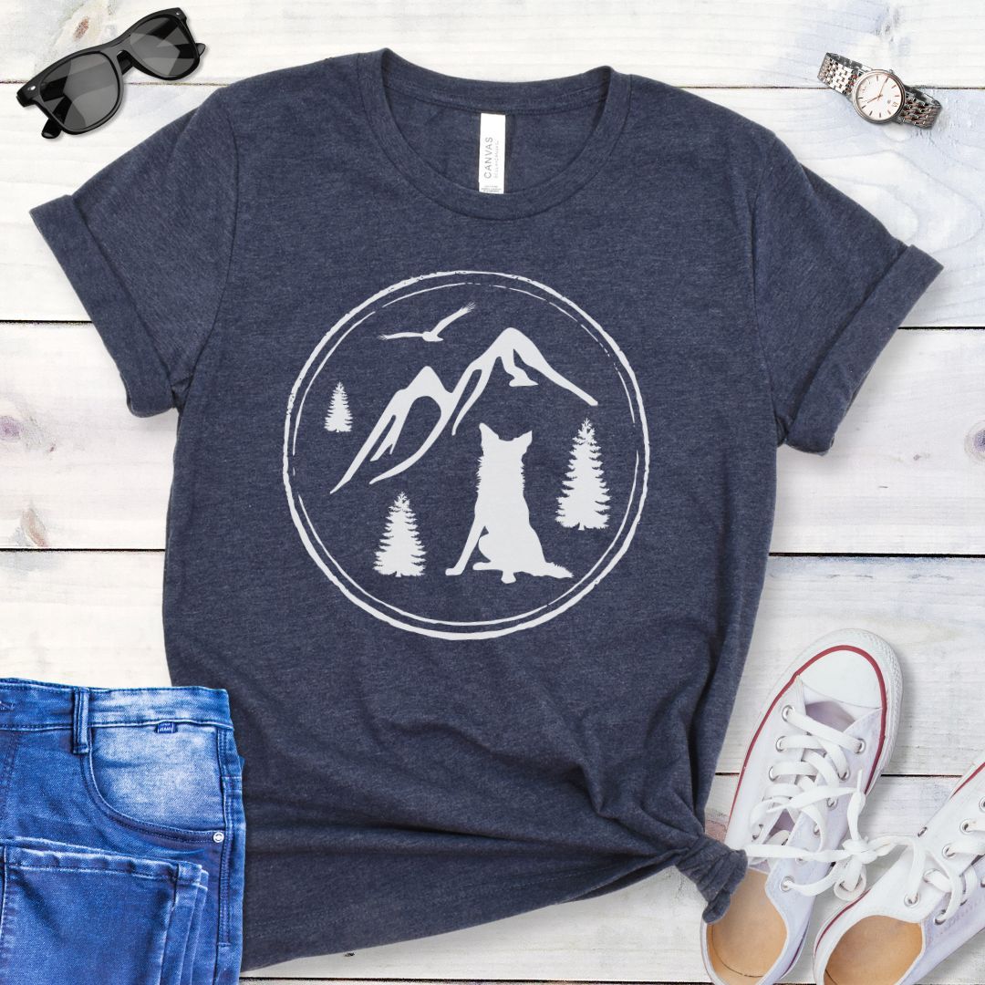 Navy t-shirt for outdoorsy dog lovers, with a minimalist mountain scene and Border Collie, shown on a wooden surface with jeans and sneakers.