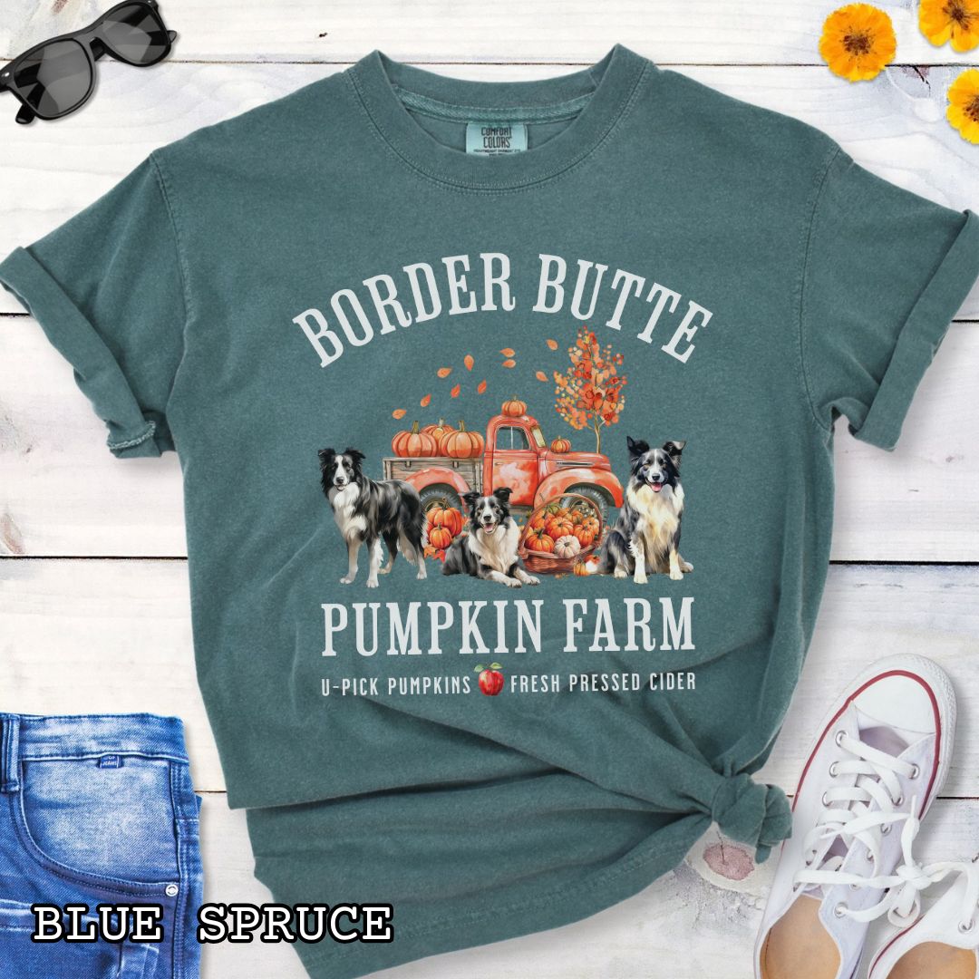 Green fall-theme t-shirt for Border Collie lovers with 'Border Butte Pumpkin Farm' design featuring Border Collies, fall foliage and a pumpkin truck, shown on a wooden surface.