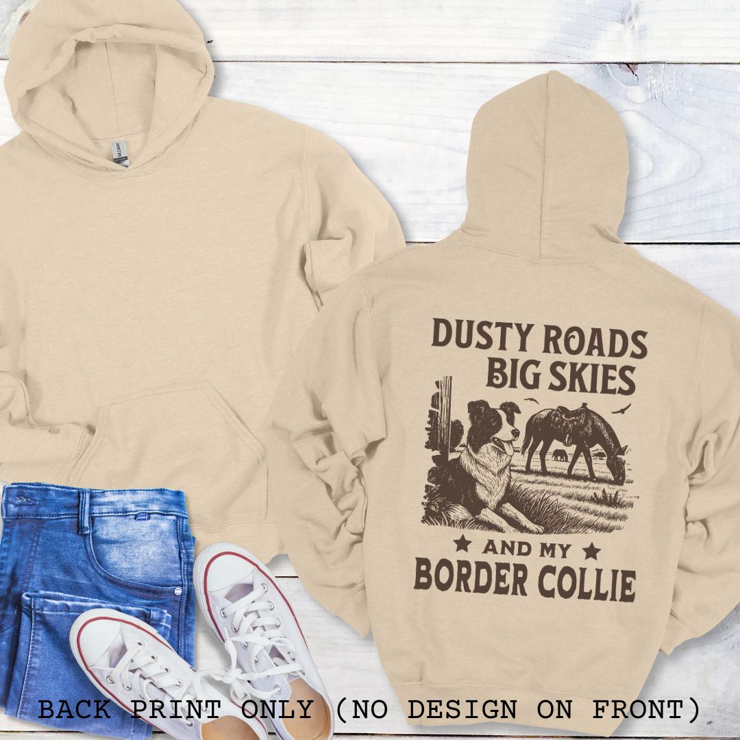 Beige hoodie with 'Dusty Roads Big Skies and My Border Collie' text and graphic on a wooden surface.