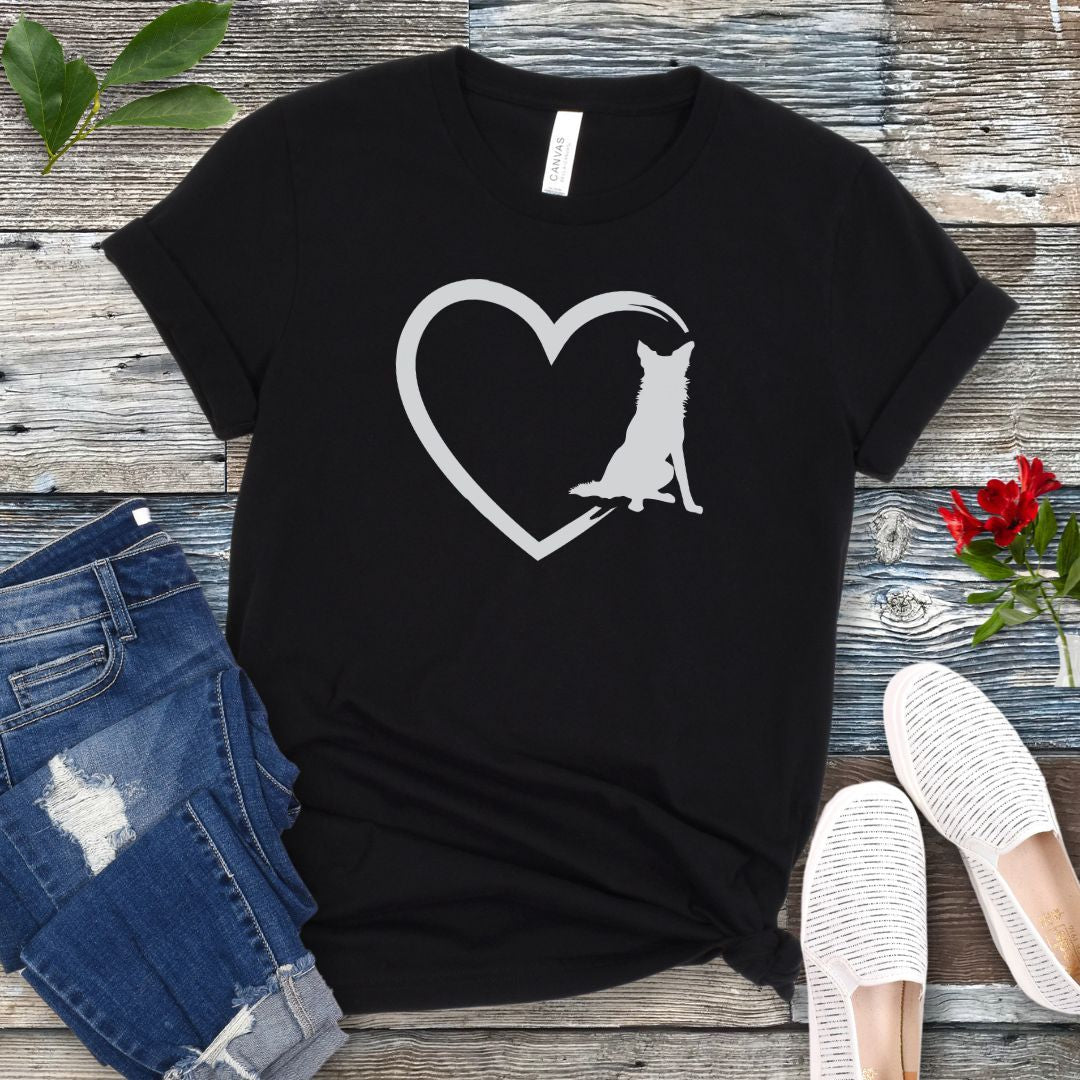 Black t-shirt for Border Collie lovers with a sketched heart intersected by a sitting Border Collie dog, shown on a wooden surface with jeans and shoes.