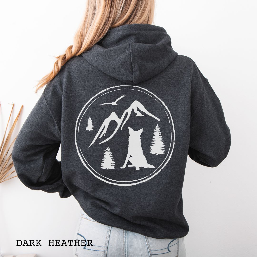 Person wearing a dark grey Border Collie back print hoodie featuring a vintage-style mountain, pine tree, and Border Collie silhouette back print for hiking enthusiasts, outdoor dog lovers, and Border Collie owners.